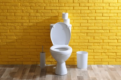 Photo of Simple bathroom interior with toilet bowl near yellow brick wall indoors. Home design