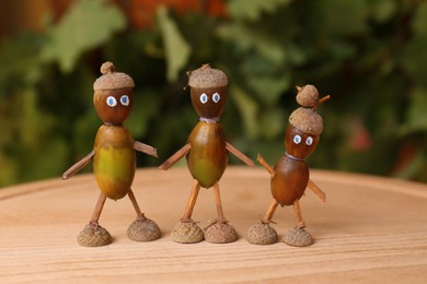 Photo of Cute figures made of acorns on wooden table