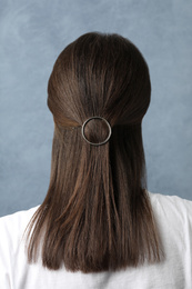 Young woman with beautiful hair clip on blue background, back view