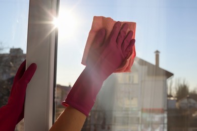 Young woman cleaning window glass with rag at home, closeup