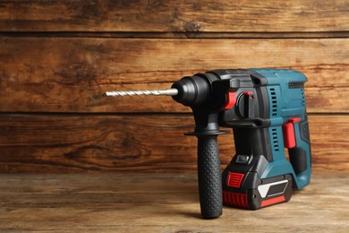 Modern electric power drill on wooden table, space for text