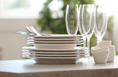 Set of clean dishware, cutlery and champagne glasses on table indoors