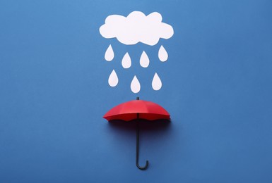 Mini umbrella and paper raindrop cloud on blue background, flat lay