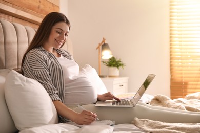 Pregnant woman working on bed at home. Maternity leave