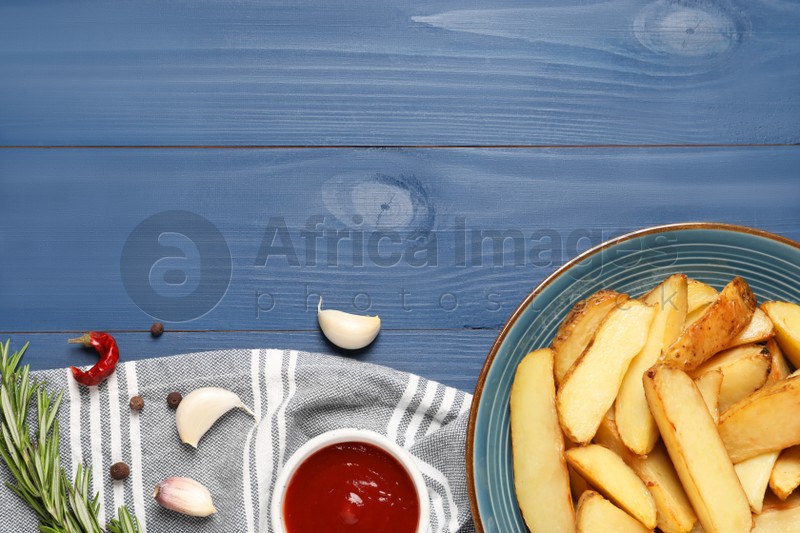 Flat lay composition with delicious baked potatoes, tomato sauce and rosemary on blue wooden table. Space for text