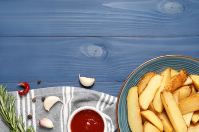 Flat lay composition with delicious baked potatoes, tomato sauce and rosemary on blue wooden table. Space for text
