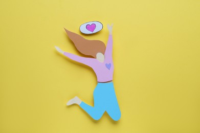 Photo of Woman`s health. Paper female figure and heart on yellow background, flat lay