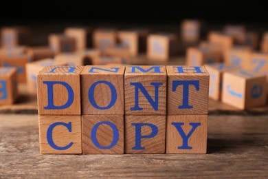 Photo of Wooden cubes with words Don't Copy on table, closeup. Plagiarism concept