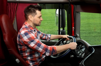 Professional driver sitting in cab of modern truck