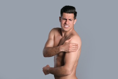 Man suffering from shoulder pain on grey background