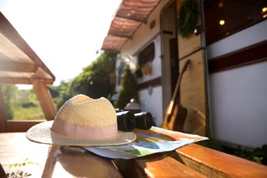 Hat and travel accessories on wooden table near motorhome. Summer trip