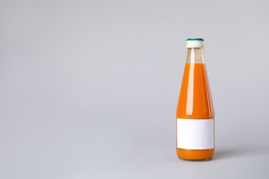 Tasty drink in bottle with blank label on color background. Mock up for design