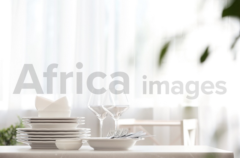 Photo of Set of clean dishware, cutlery and wineglasses on table indoors. Space for text