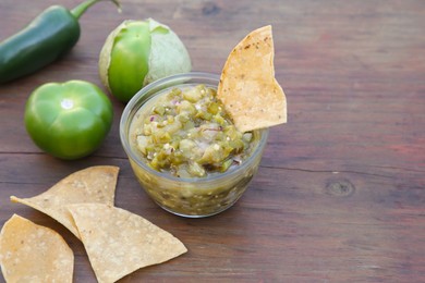 Photo of Tasty salsa sauce, ingredients and tortilla chips on wooden table, closeup. Space for text
