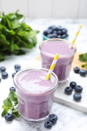Photo of Tasty blueberry smoothie with mint and fresh berries on white marble table, closeup