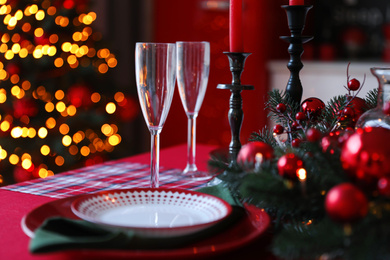 Table served for festive dinner and blurred Christmas tree in stylish kitchen interior, closeup