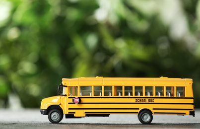 Yellow school bus on table against blurred background. Transport service