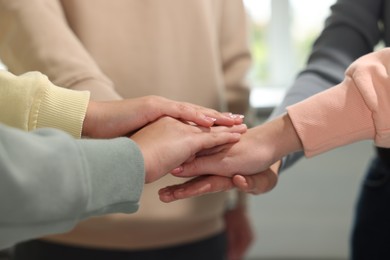 Photo of Group of people holding hands together indoors, closeup. Unity concept