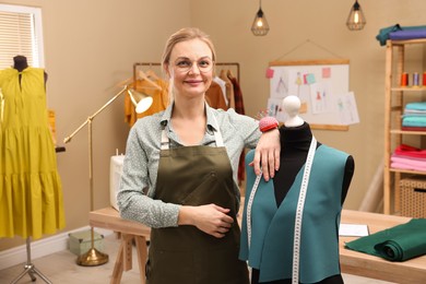 Photo of Portrait of dressmaker near mannequin in workshop