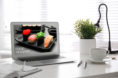Modern laptop with open page of food delivery service on screen