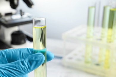 Doctor holding test tube with urine sample for analysis in laboratory, closeup. Space for text