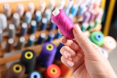 Photo of Dressmaker with pink thread near stand indoors, closeup