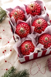 Photo of Box with red Christmas baubles on knitted plaid, above view