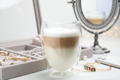 Delicious latte near jewelry box on white table