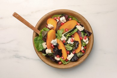 Photo of Delicious persimmon salad with cheese and pomegranate on white marble table, top view
