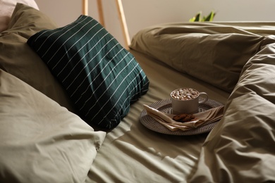 Cup of drink and cookies on bed with new pistachio linens in room