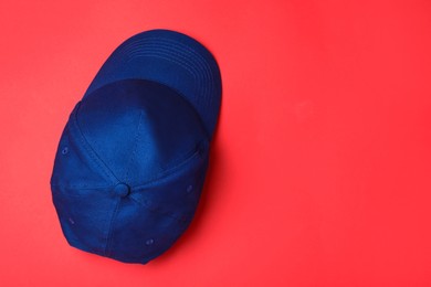 Stylish blue baseball cap on red background, top view. Space for text
