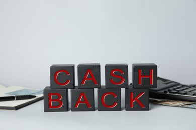 Word Cashback made with cubes, money and calculator on grey background