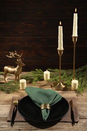 Stylish table setting with green fabric napkin, beautiful decorative ring and festive decor on wooden background
