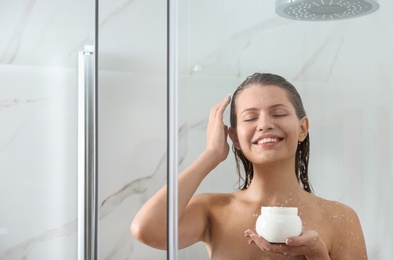 Beautiful young woman applying hair mask in shower at home. Space for text