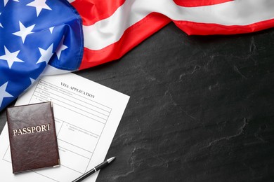 Photo of American flag, visa application form and passport on black table, flat lay. Space for text