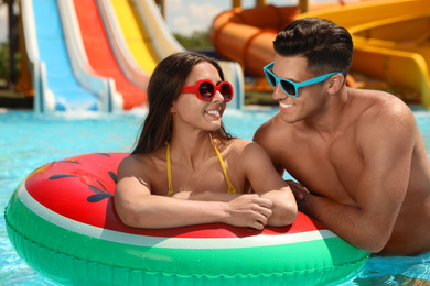 Happy couple with inflatable ring at water park. Summer vacation
