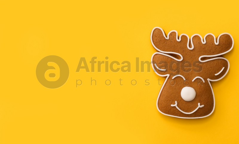 Christmas deer shaped gingerbread cookie on yellow background, top view. Space for text