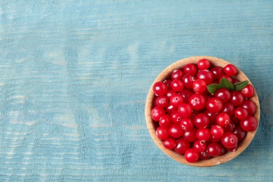 Tasty ripe cranberries on light blue wooden table, top view. Space for text