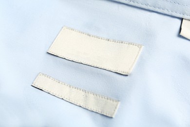Blank clothing labels on light blue shirt, closeup
