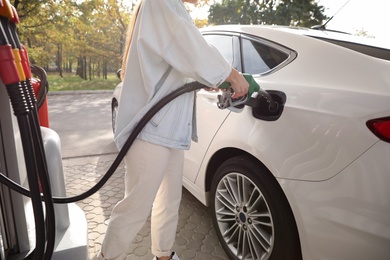 Woman refueling car at self service gas station, closeup