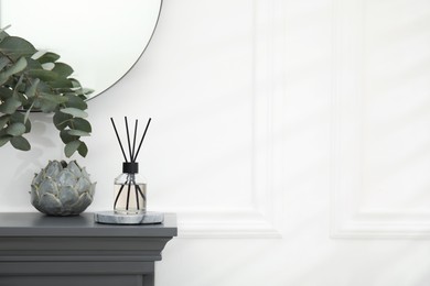 Reed diffuser and home decor on grey table near white wall. Space for text