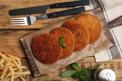 Delicious fried breaded cutlets served on wooden table, flat lay