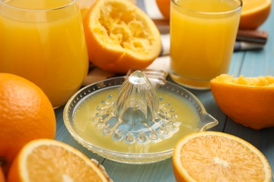 Squeezer, fresh oranges and juice on blue wooden table