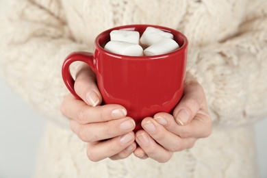 Woman in sweater holding cup of delicious marshmallow cocoa, closeup
