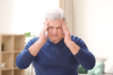 Mature man suffering from headache at home