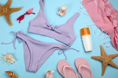 Flat lay composition with swimsuit and beach accessories on light blue background