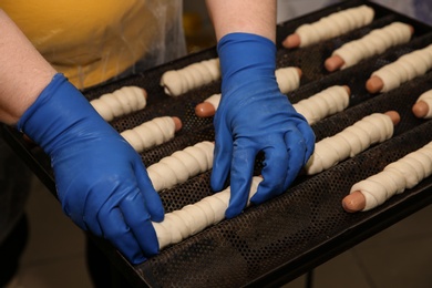 Baker putting sausage rolls on tray in workshop, closeup