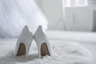 White wedding shoes on furry rug in room, back view. Space for text