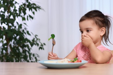 Cute little girl refusing to eat her breakfast at home, space for text
