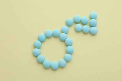 Male sign with bent arrow of blue pills symbolizing potency problems on beige background, flat lay